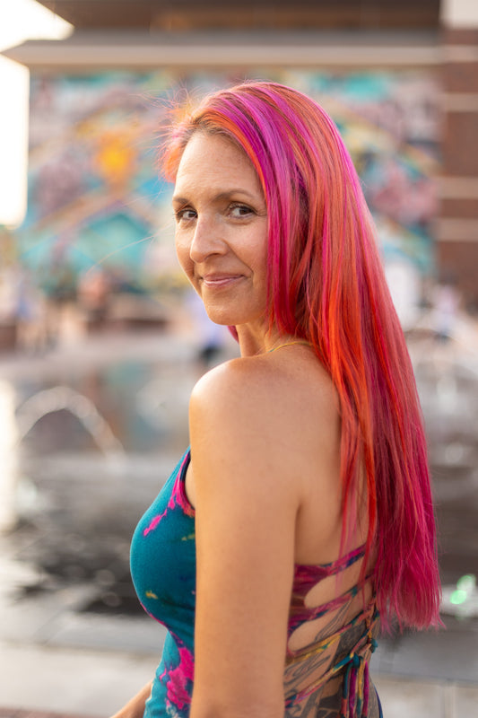 Portrait of Katy L. Casillas-Gray, co-owner of The Painted Moth, smiling warmly with a creative and colorful background, reflecting her vibrant personality and artistic passion.